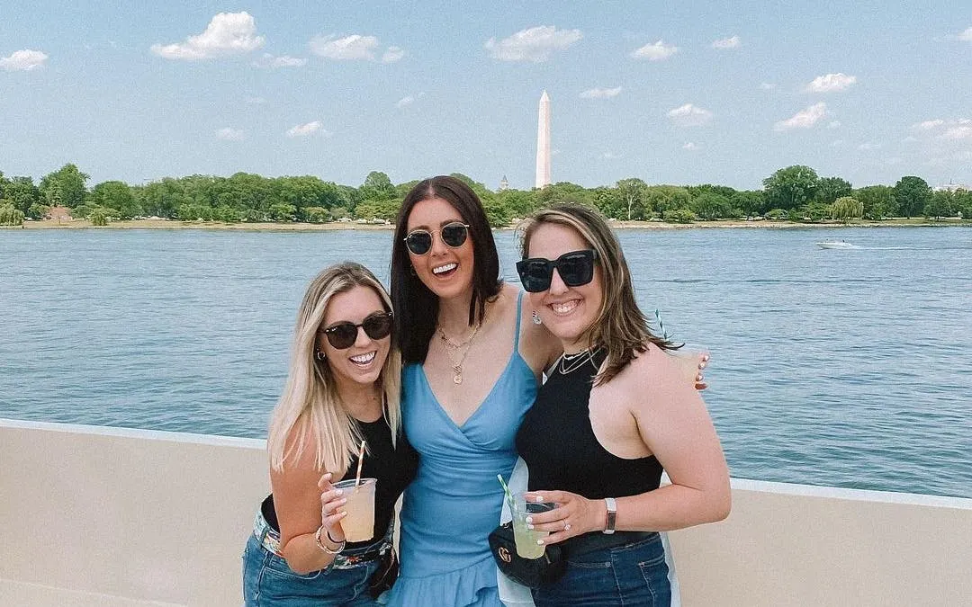 Three people enjoying drinks on a yacht with Washington Monument in the background, Washington, DC.