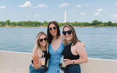 Three people enjoying drinks on a yacht with Washington Monument in the background, Washington, DC.