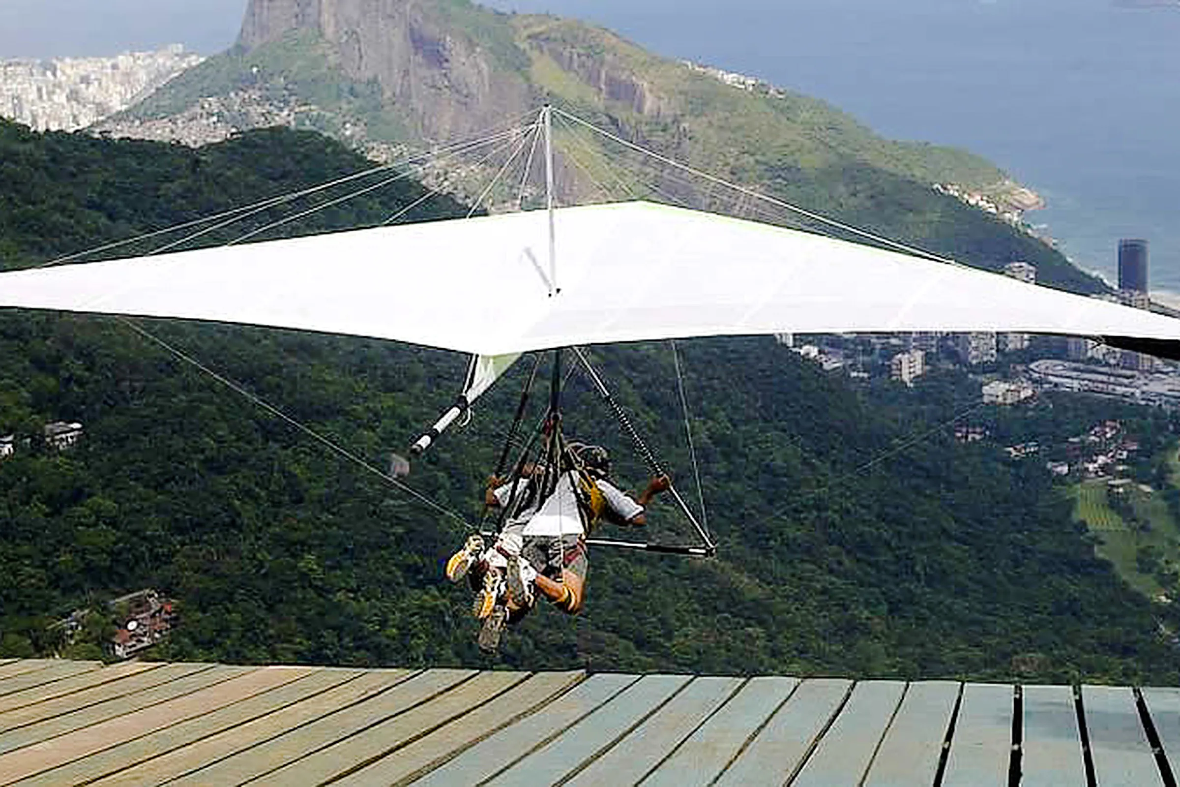 Tandem hang gliding launch from Pedra Bonita with Rio de Janeiro cityscape below.