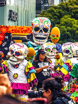 Colorful Day of the Dead parade with people in skull costumes, Mexico.