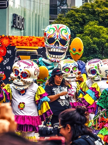 Colorful Day of the Dead parade with people in skull costumes, Mexico.