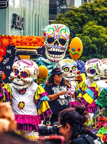 Colorful Day of the Dead parade with people in skull costumes, Mexico.
