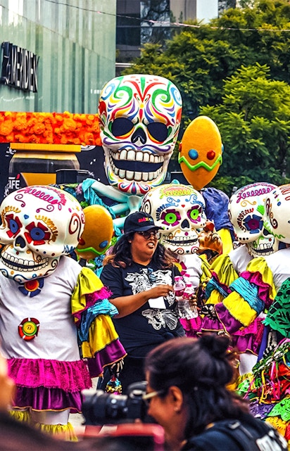 Colorful Day of the Dead parade with people in skull costumes, Mexico.