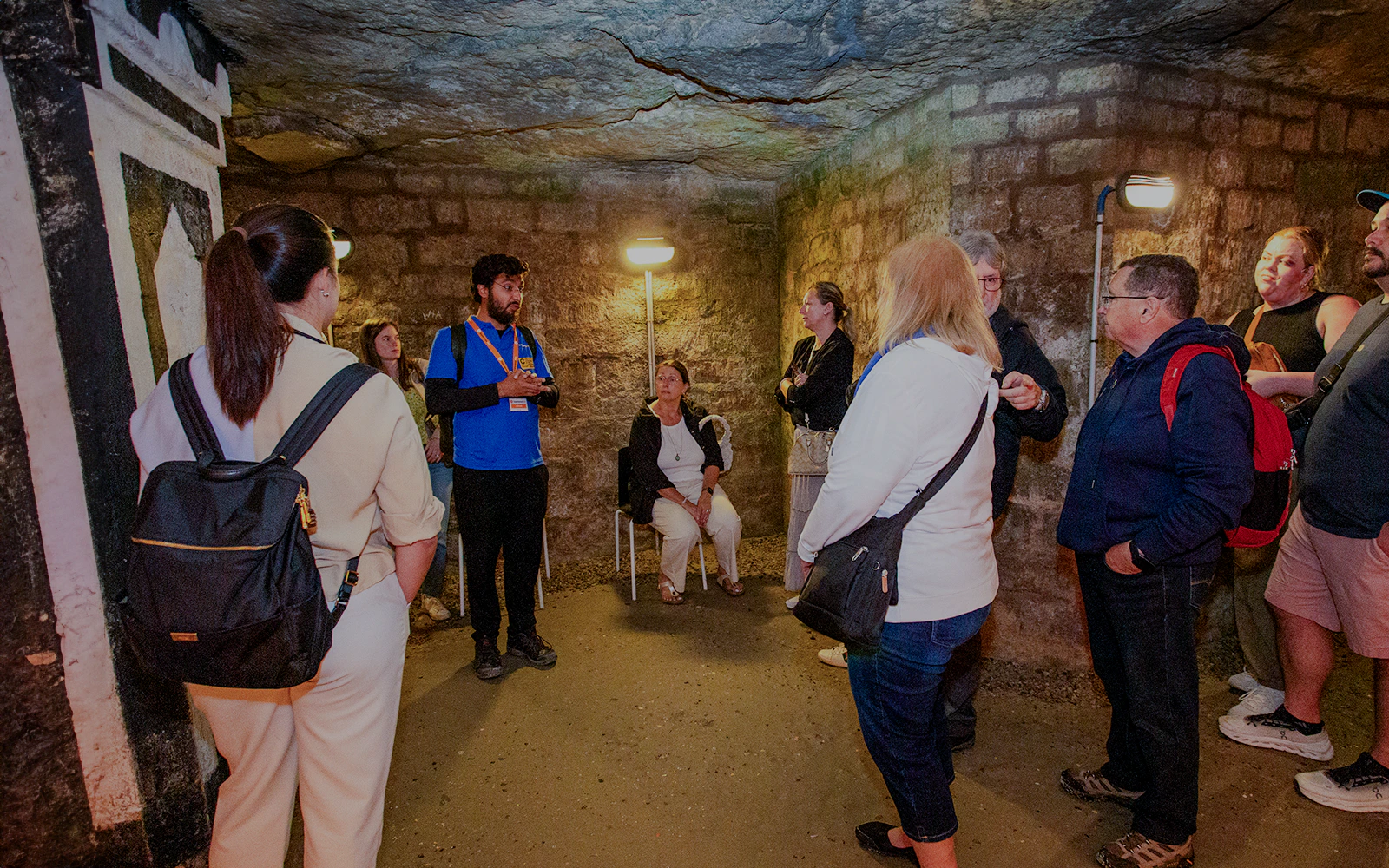 Group listening to a guide in the Paris Catacombs during a tour.
