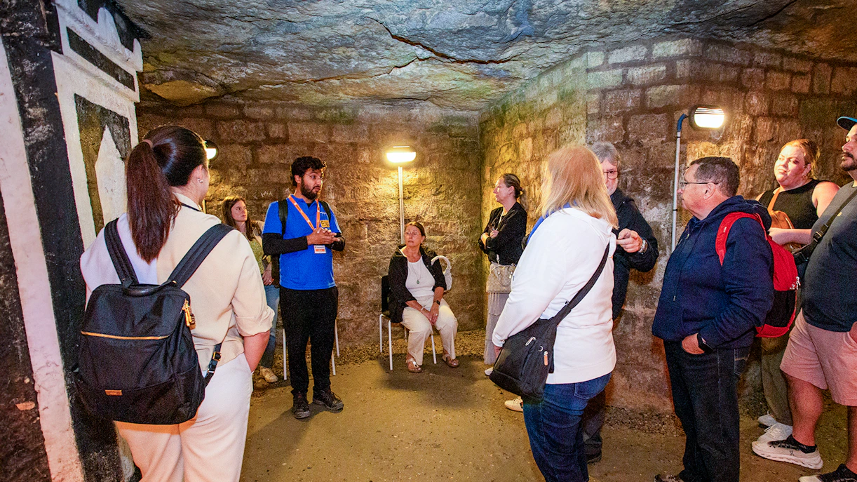 Group listening to a guide in the Paris Catacombs during a tour.