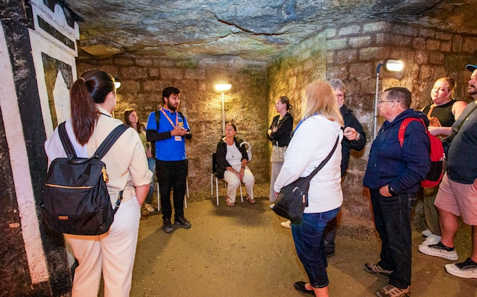 Group listening to a guide in the Paris Catacombs during a tour.