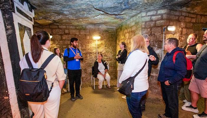 Group listening to a guide in the Paris Catacombs during a tour.