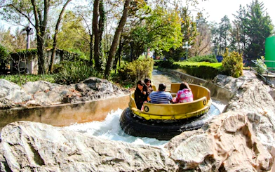 Raft navigating wild river ride at Six Flags Mexico amidst trees and rocks.