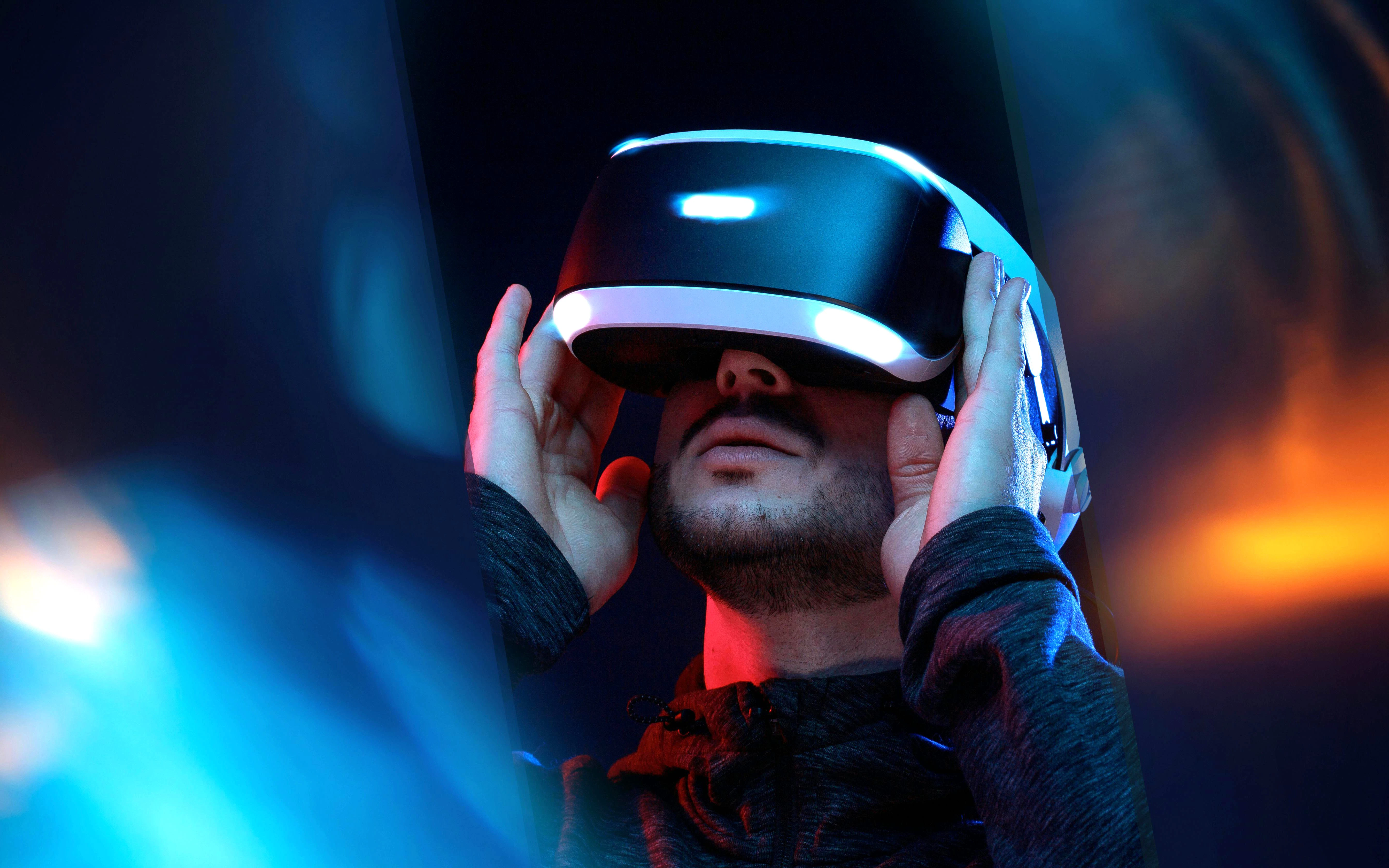 Young man using VR headset with neon lights, exploring augmented reality technology.
