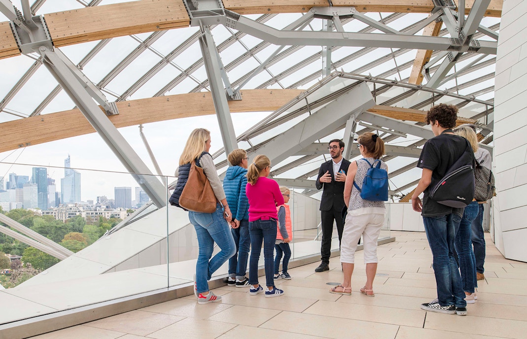 Tour group at Fondation Louis Vuitton in Paris with guide explaining architecture.