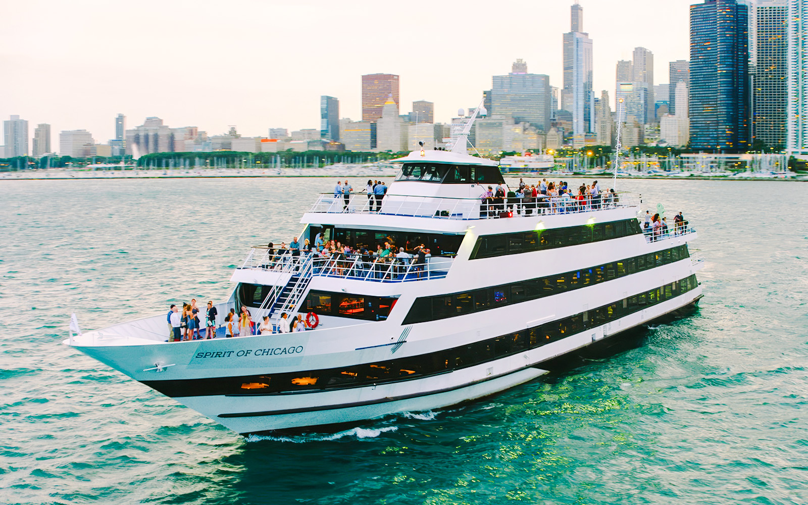 Cruise ship on Chicago River with city skyline in background.