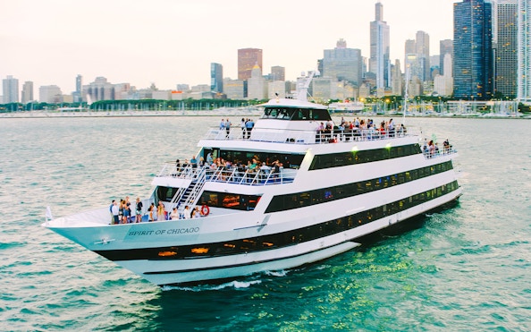 Cruise ship on Chicago River with city skyline in background.