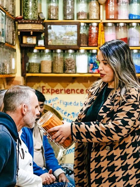 Shopkeeper showing spices to tourists in a Marrakech souk during a private shopping tour.