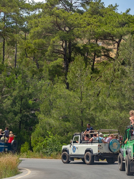 Jeeps with tourists driving through forested area in Antalya during guided safari tour.