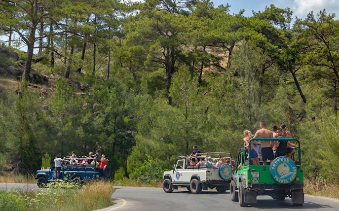 Jeeps with tourists driving through forested area in Antalya during guided safari tour.