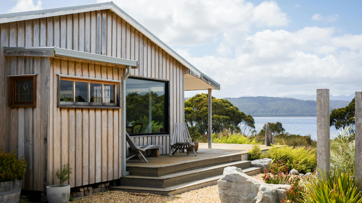Timber cabin verandah overlooking scenic lake and mountains, ideal for holiday escape.