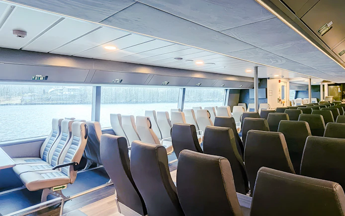 Interior seating of Geiranger Silent Fjord Cruise ship with large windows overlooking the water.