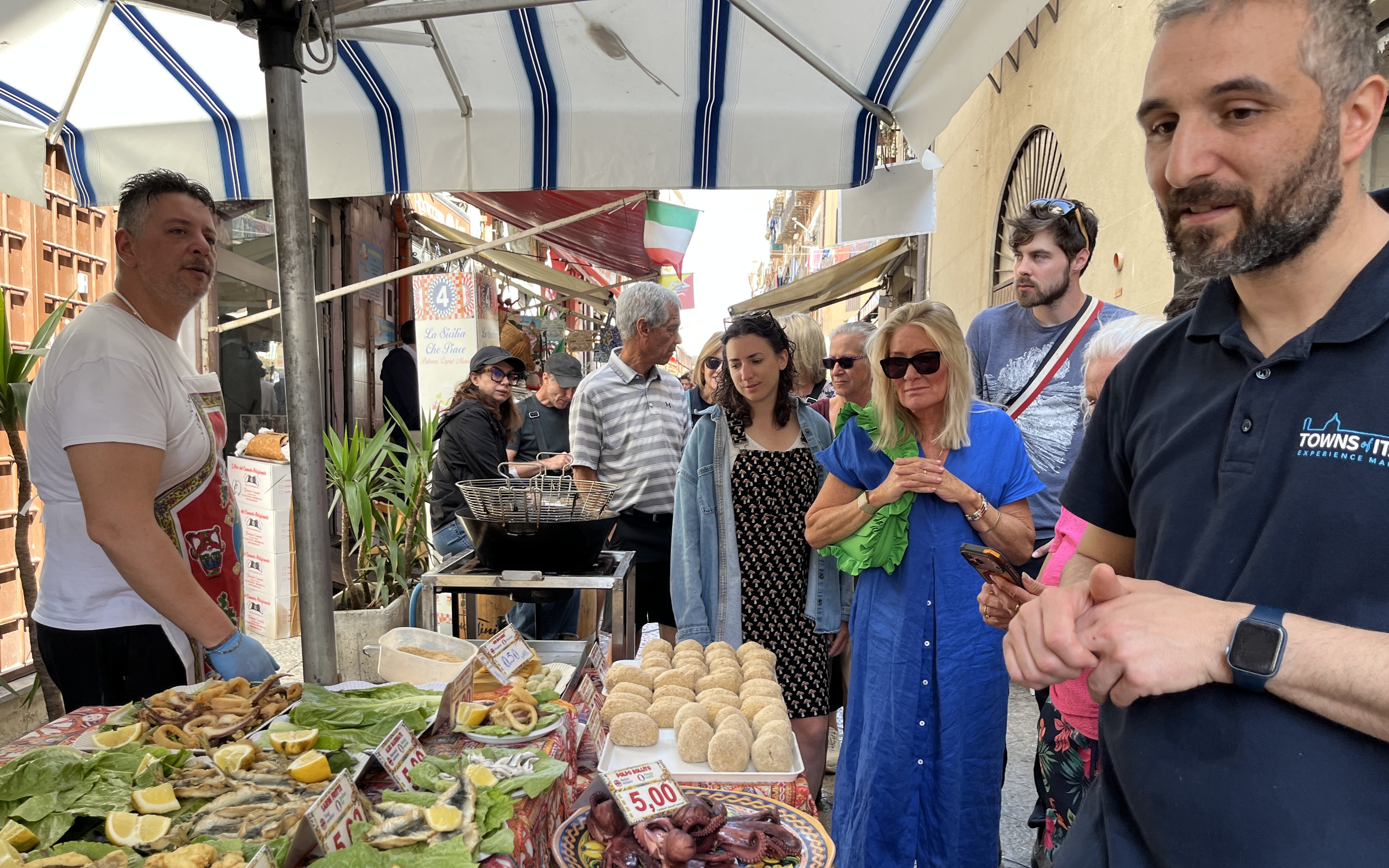 Palermo market tour group observing local street food vendor with fresh seafood display.