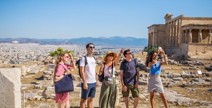 Guided tour group exploring the Acropolis of Athens with Parthenon in the background.