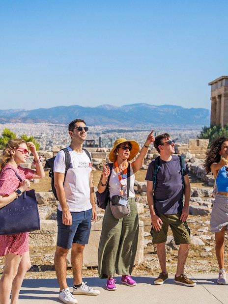 Tourists exploring the Acropolis of Athens with the Erechtheion in the background.