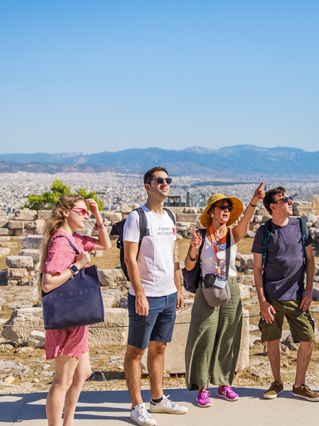 Tourists exploring the Acropolis of Athens with the Erechtheion in the background.