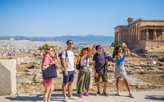 Tourists exploring the Acropolis of Athens with the Erechtheion in the background.