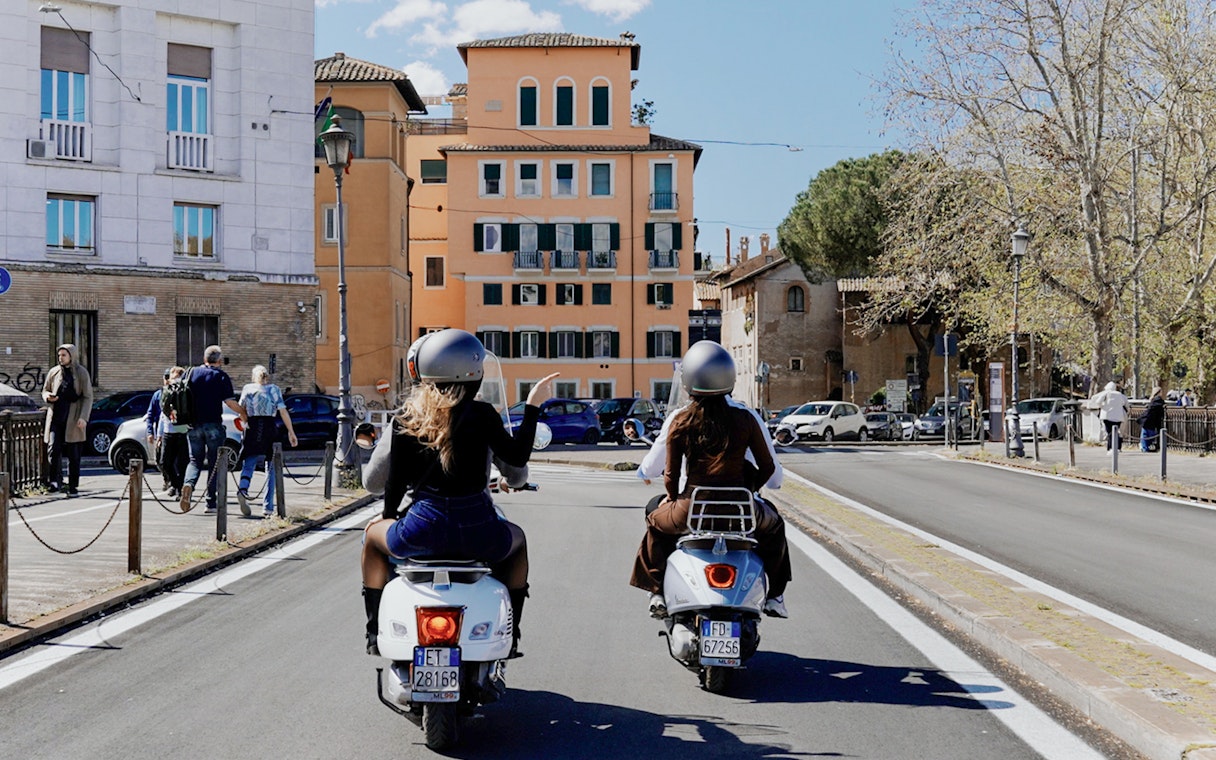 Tourists on Vespas riding through a street in Rome, Italy.