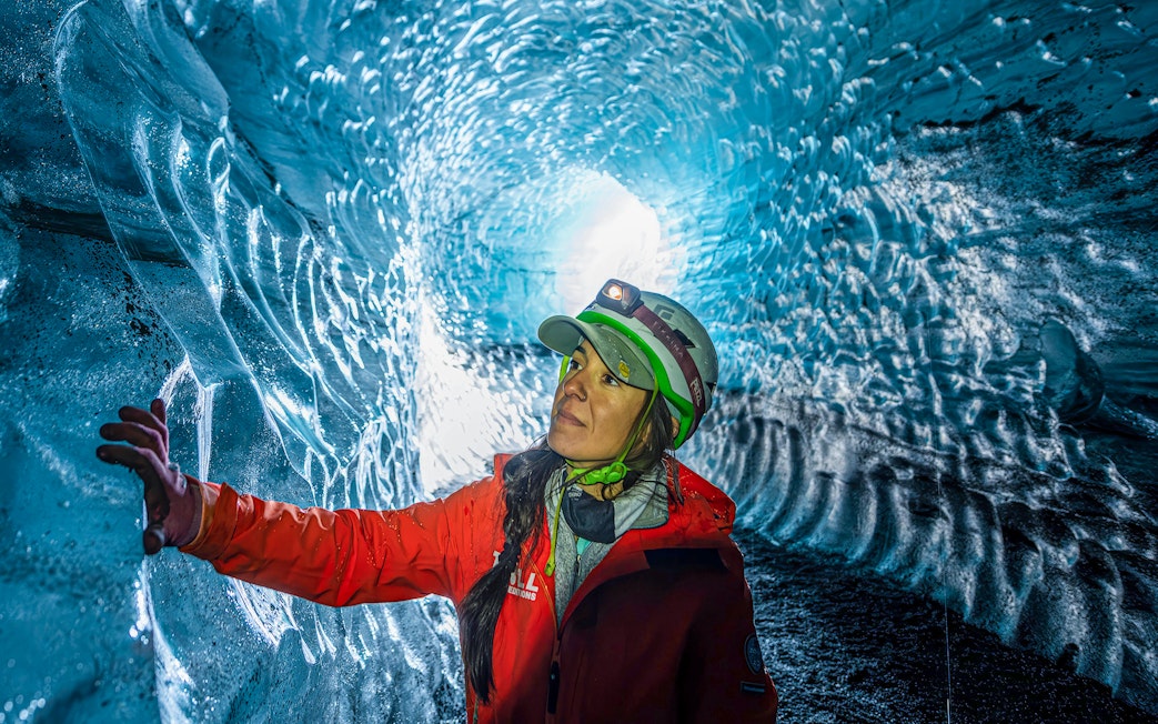 Person exploring the icy walls of Katla Ice Cave, Iceland.