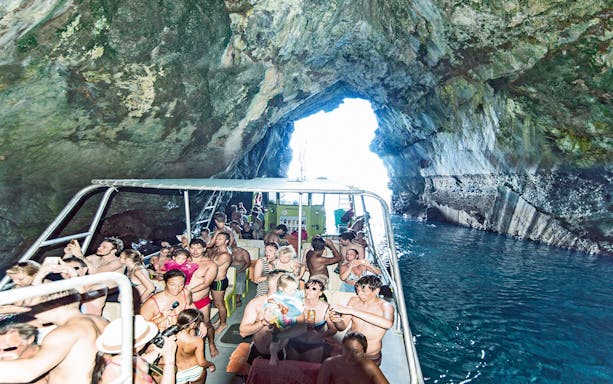 Boat tour with people exploring a cave in Alcudia, Mallorca.
