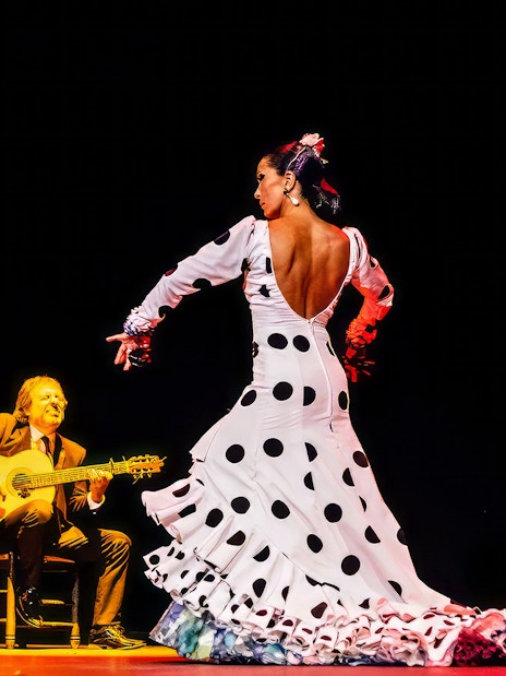 Flamenco dancer performing with musicians on stage at Esencia show.