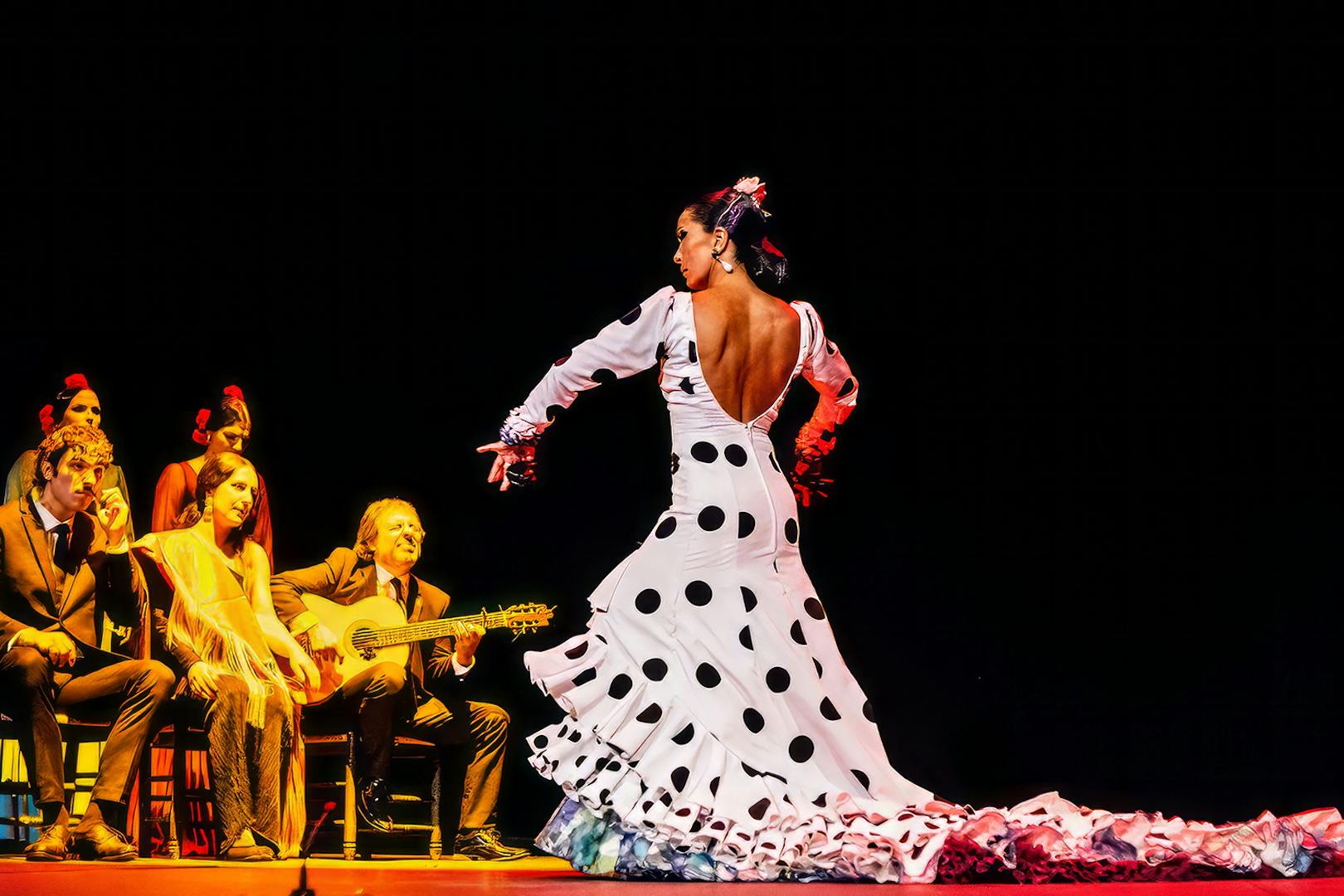 Flamenco dancer performing with musicians on stage at Esencia show.