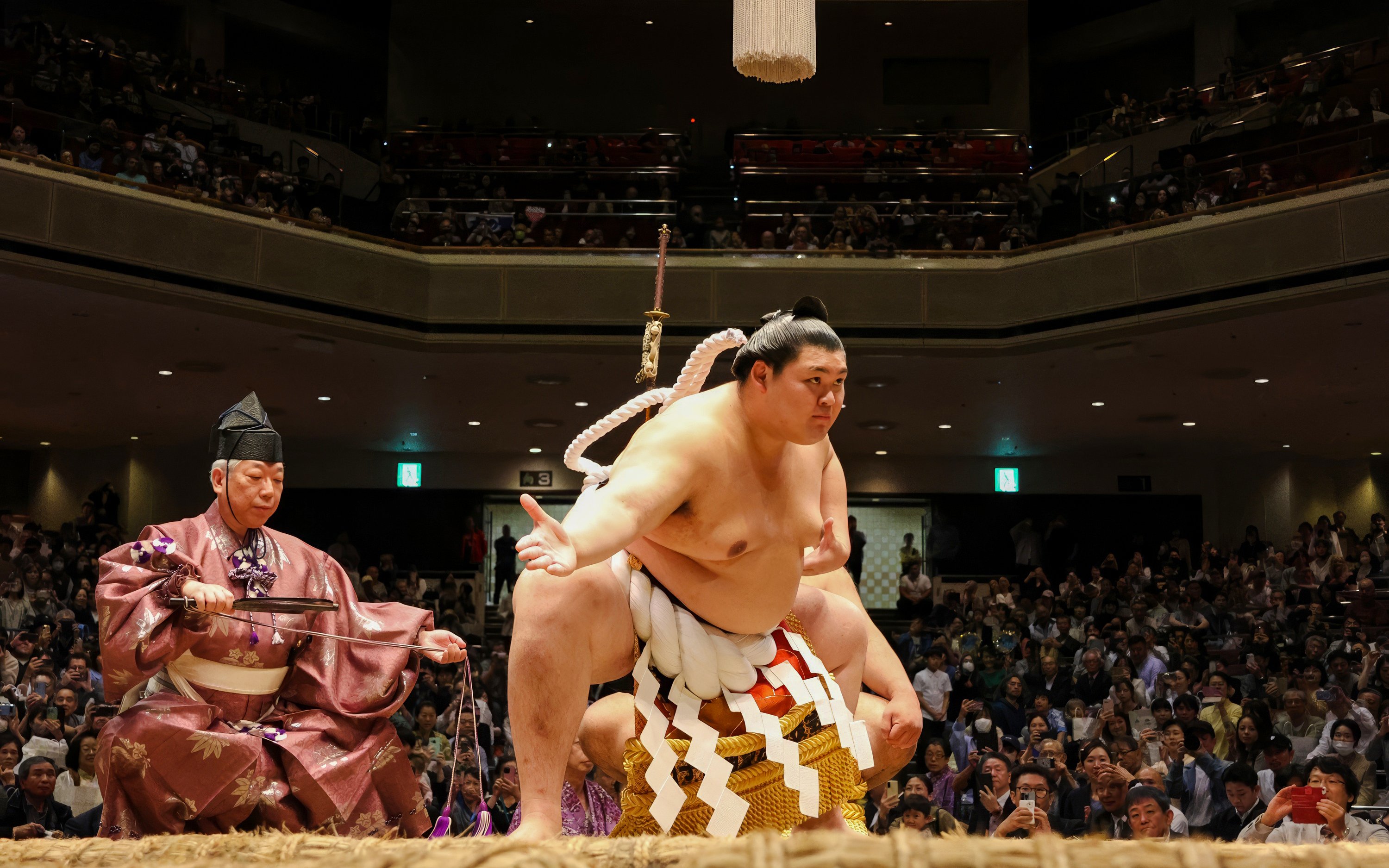 Sumo wrestler performing on stage in front of an audience in Japan.
