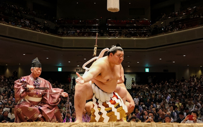 Sumo wrestler performing on stage in front of an audience in Japan.
