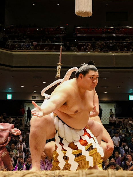 Sumo wrestler performing on stage in front of an audience in Japan.