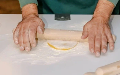Hands rolling pasta dough during a cooking class in Rome.