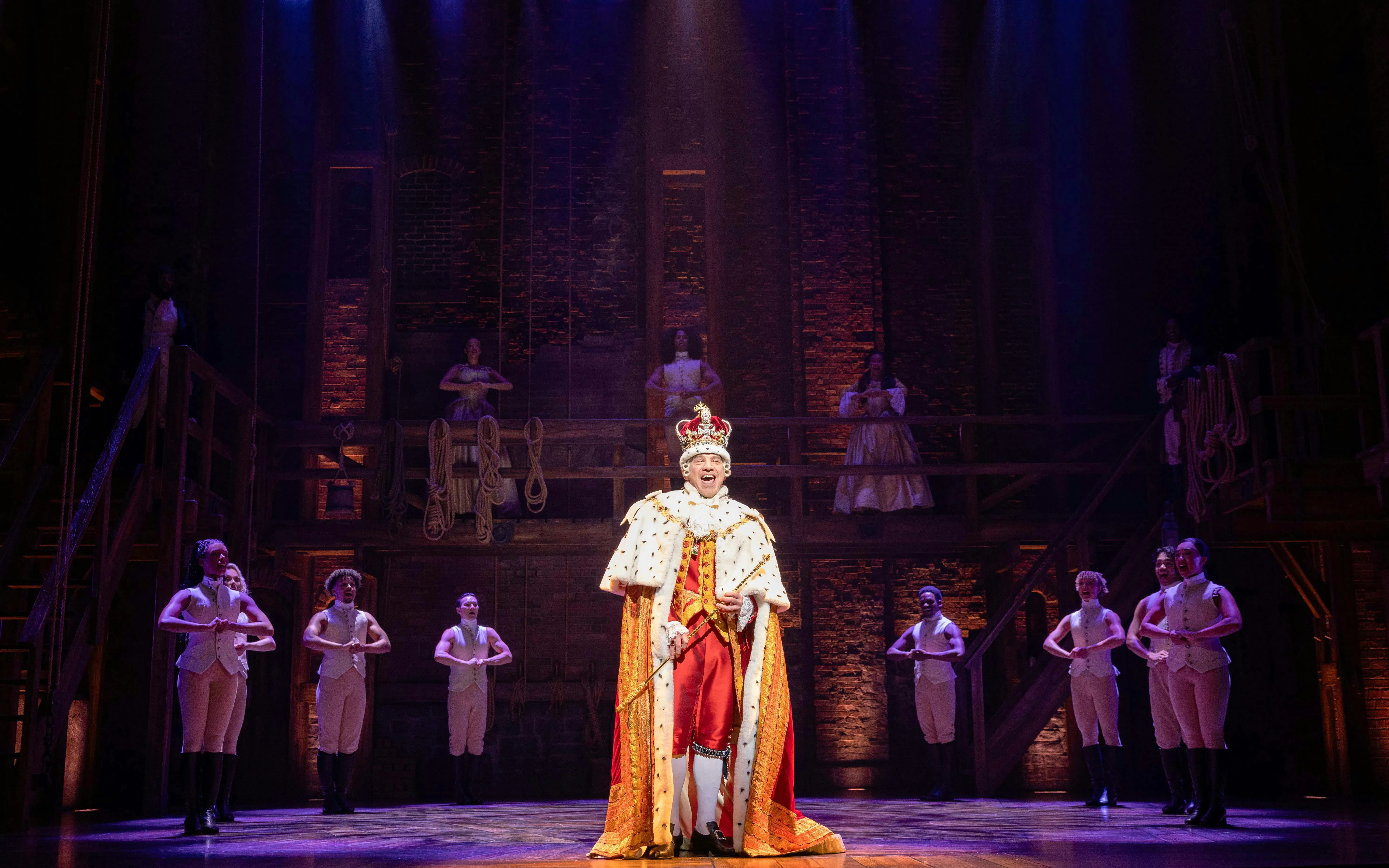 Hamilton West End performance with actor in royal costume on stage.