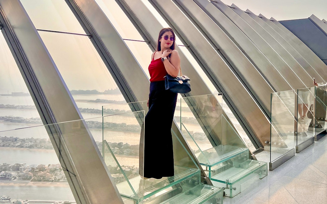 Woman enjoying the view at The View At The Palm, Dubai, with cityscape in the background.