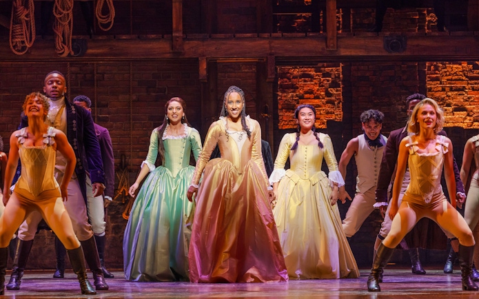 Cast performing on stage in a scene from the musical Hamilton.