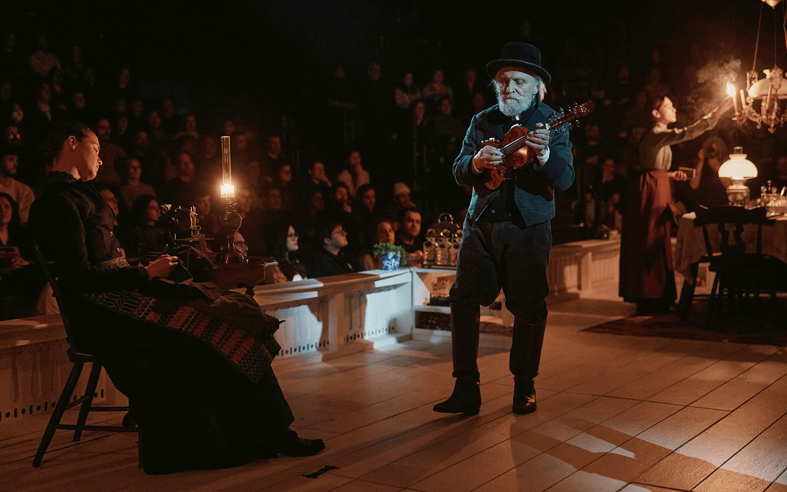 Theater performance of "An Enemy of the People" with a musician playing a violin on stage.