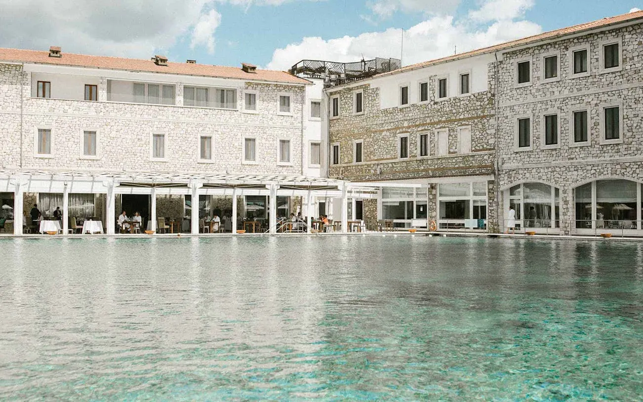 Thermal club pool area with stone buildings and outdoor dining tables.