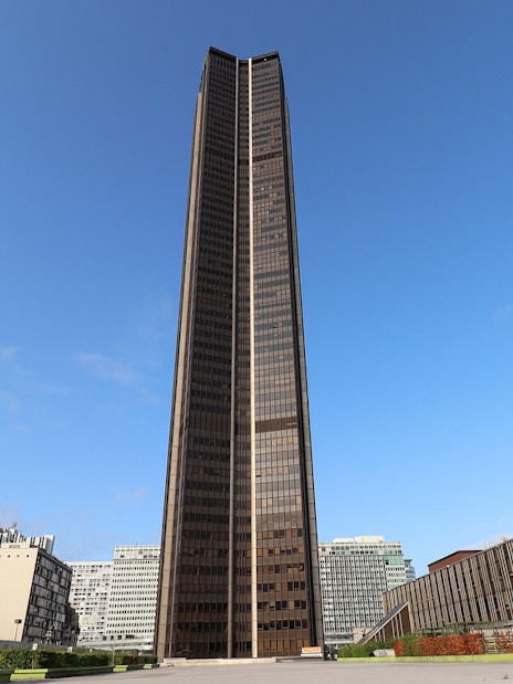 Montparnasse Tower in Paris under a clear blue sky.