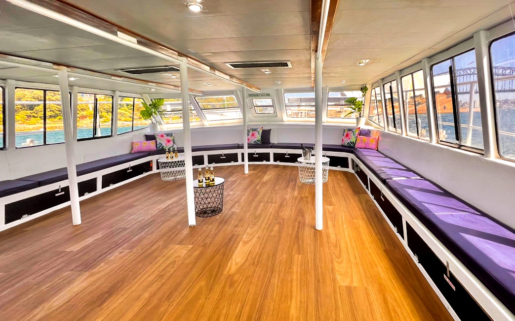 Interior of a boat with seating and tables, part of the Sydney Whale Watching Adventure Cruise.