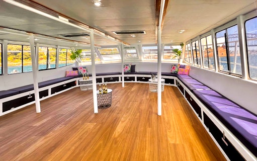 Interior of a boat with seating and tables, part of the Sydney Whale Watching Adventure Cruise.