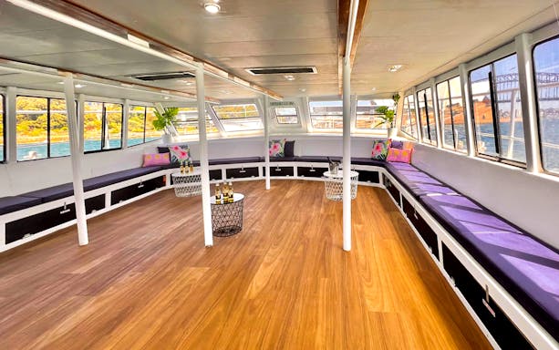 Interior of a boat with seating and tables, part of the Sydney Whale Watching Adventure Cruise.