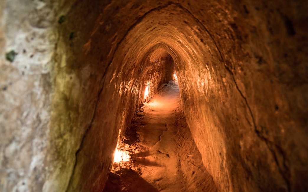 Narrow passage inside Cu Chi Tunnels, Vietnam, dimly lit with warm lights.