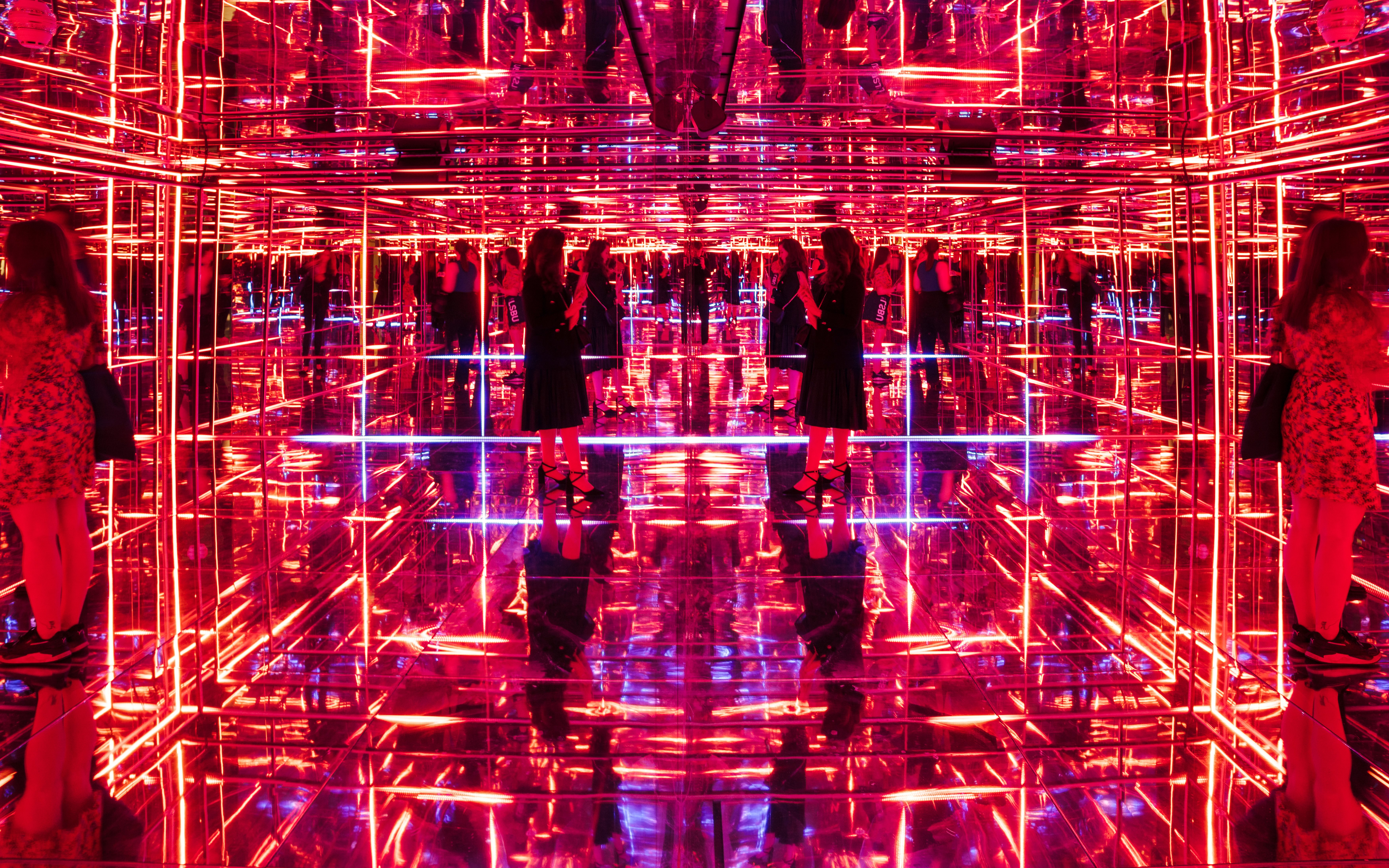 Visitors exploring neon-lit mirrored room at Moco Museum London interactive exhibit.