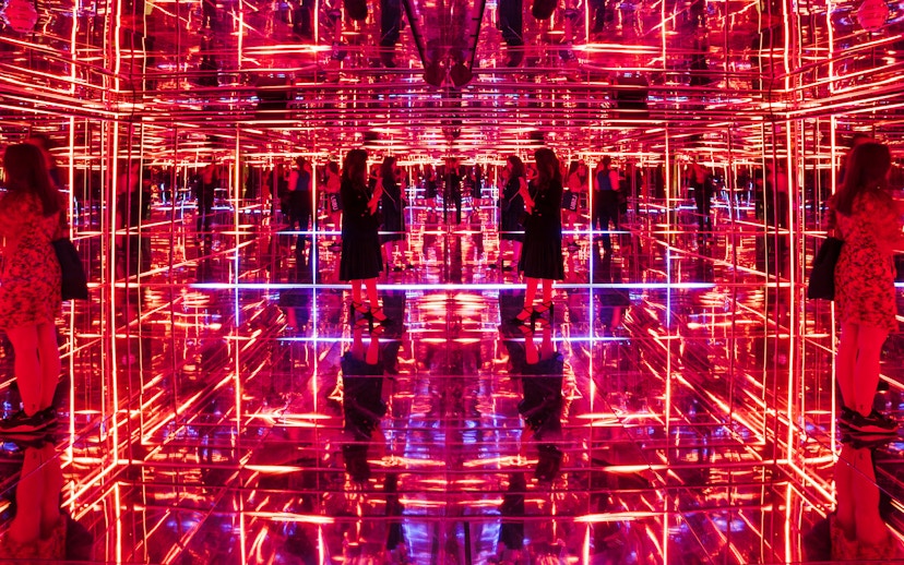 Visitors exploring neon-lit mirrored room at Moco Museum London interactive exhibit.