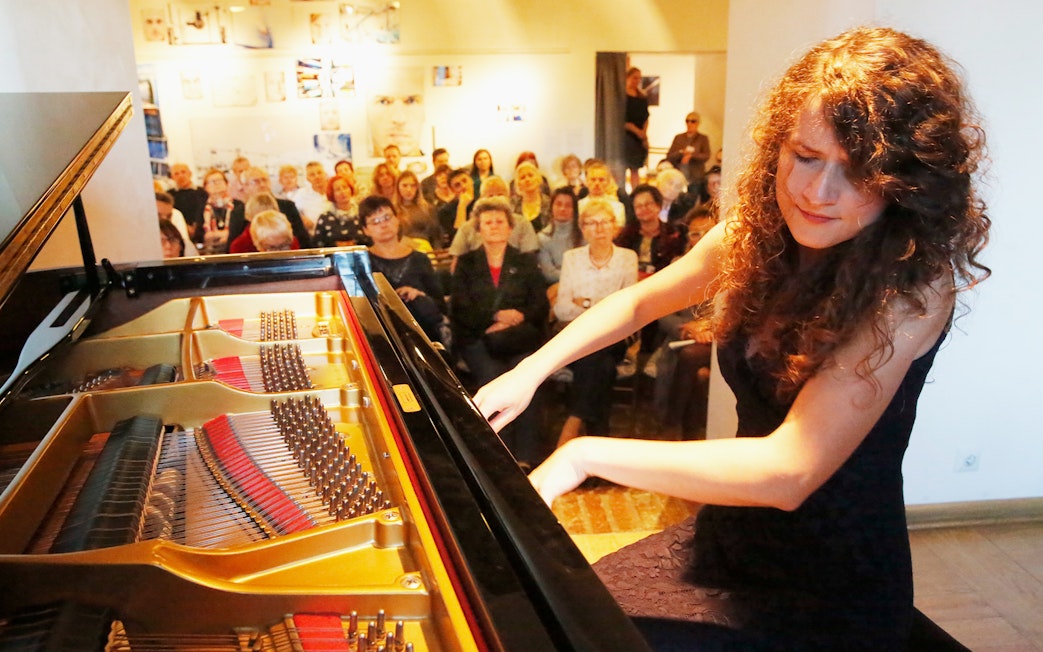 Pianist performing Chopin at Old Town recital with audience in background.