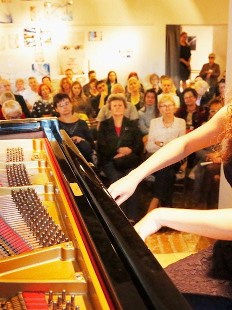 Pianist performing Chopin at Old Town recital with audience in background.