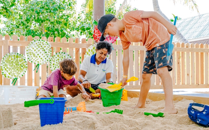 Children playing in a sandbox with a guide at South Sea Island, Fiji.